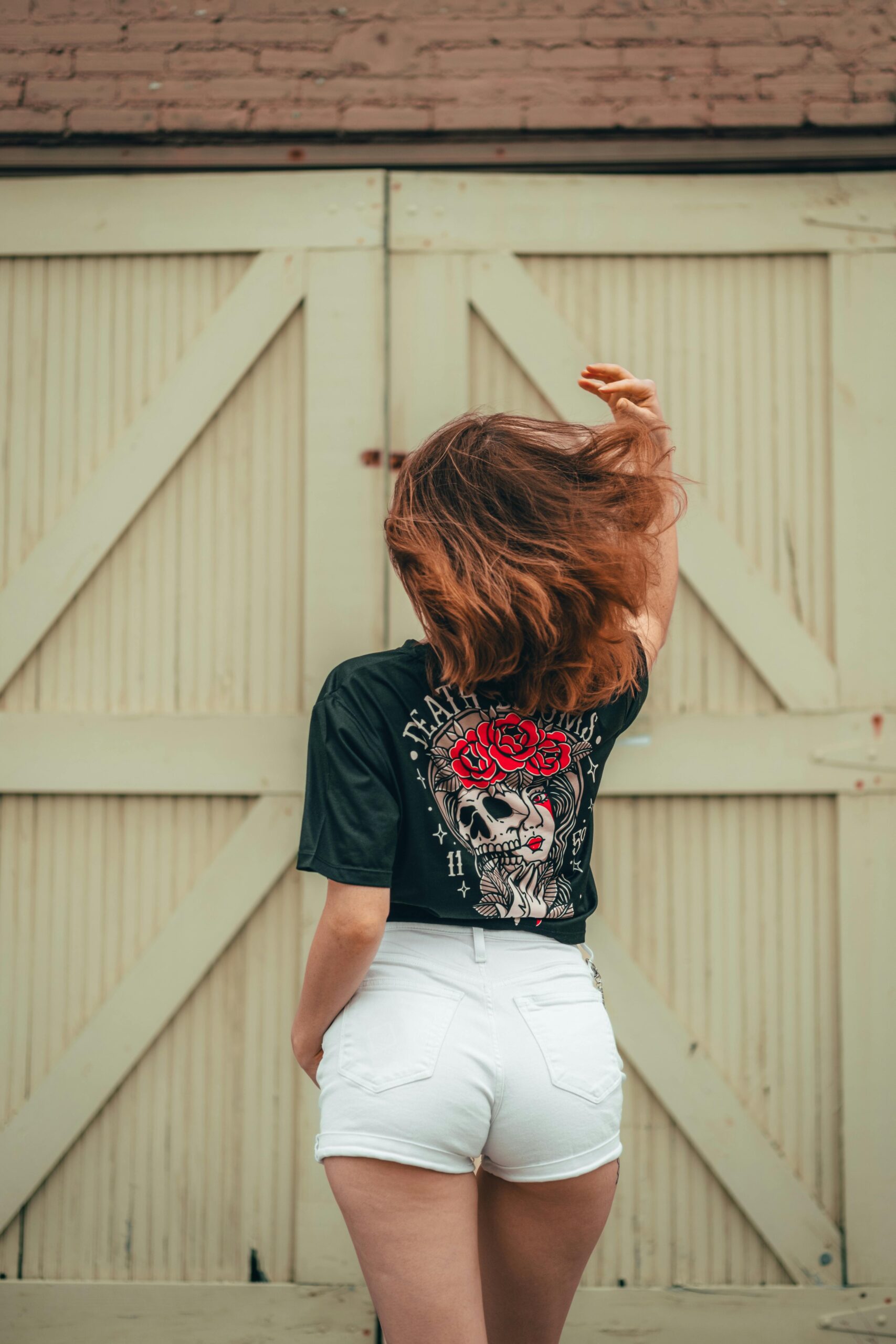 Woman with back turned, wearing shorts and printed t-shirt in urban background.