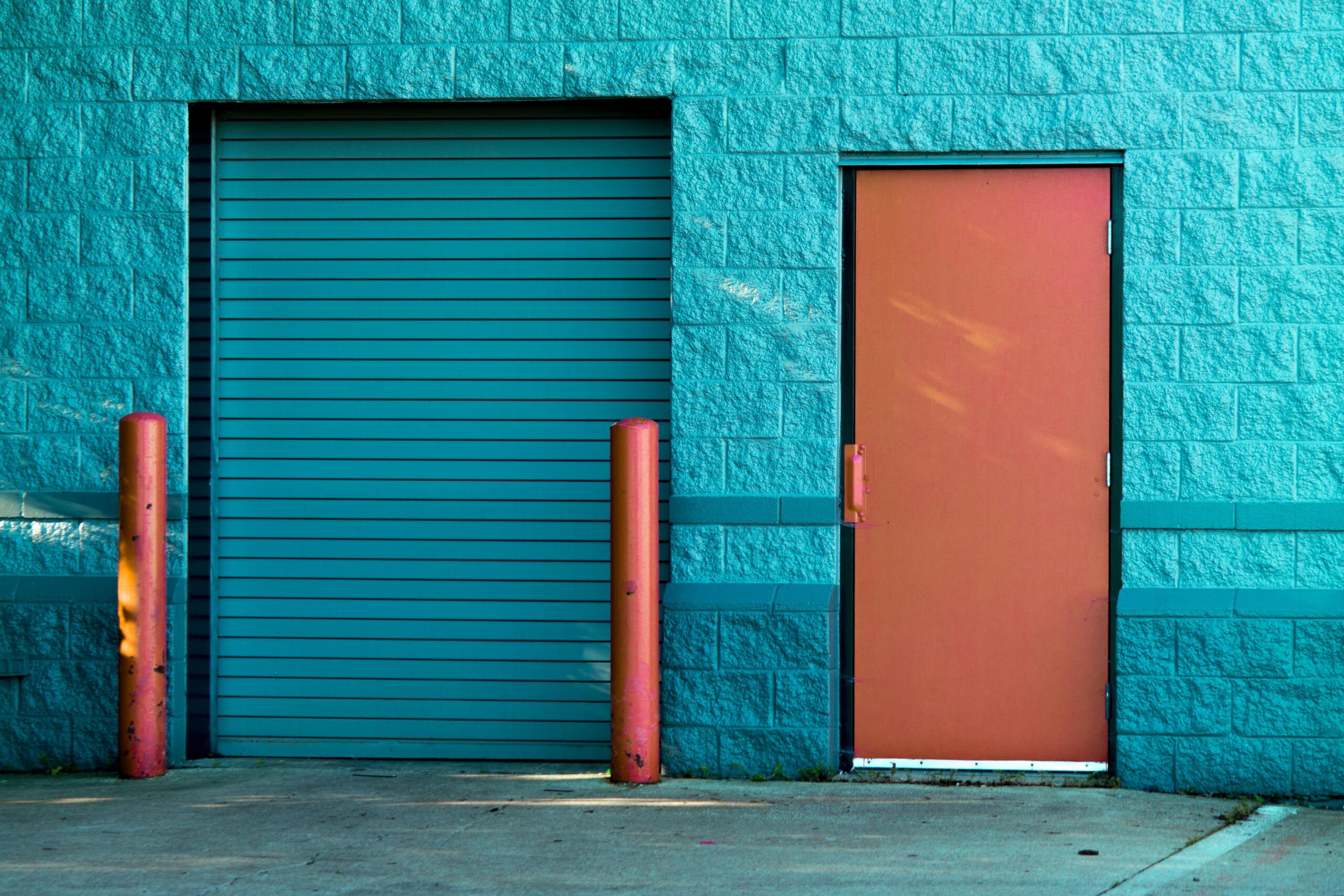 Vivid blue wall with a closed door and shutter in Valparaiso's urban setting.